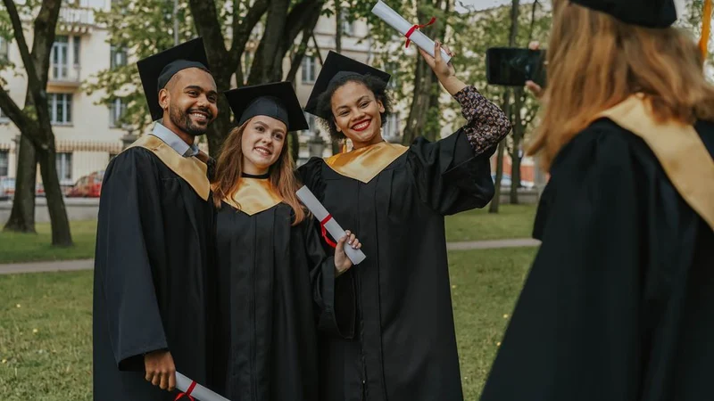 Group of diverse students celebrating graduation outdoors with diplomas