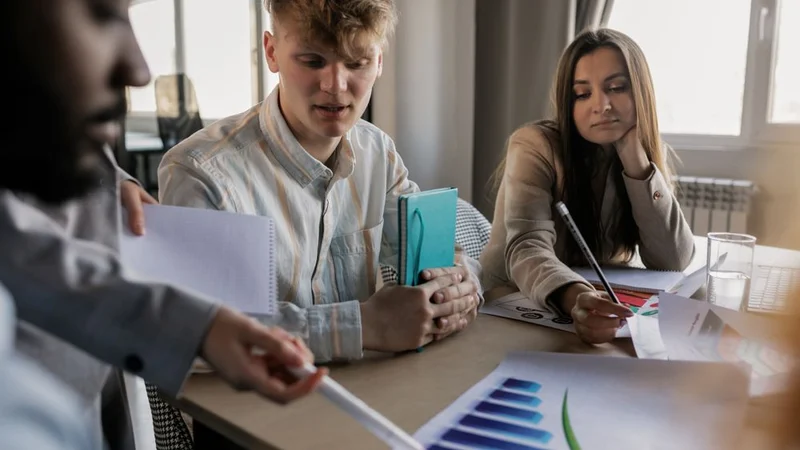 A diverse team of young professionals engaged in a business meeting analyzing graphs and data