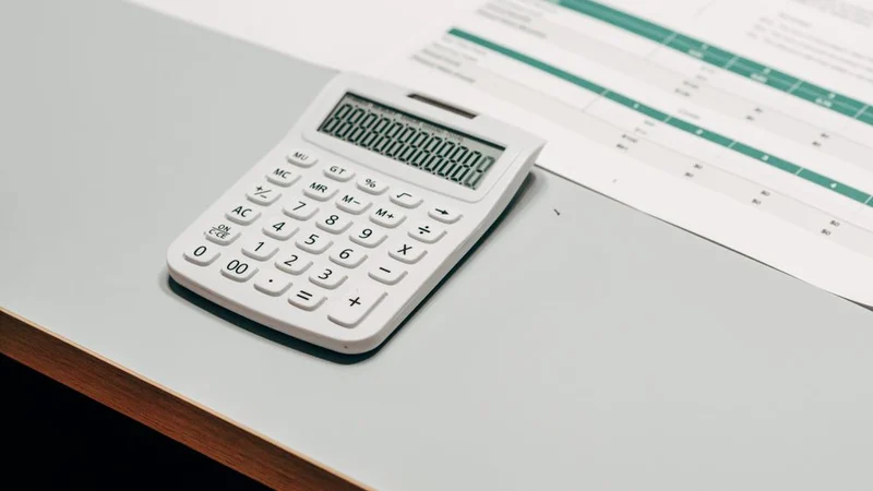 Close-up of a white calculator next to a financial spreadsheet on a desk